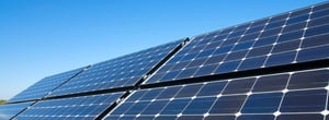 Nahaufnahme einer Solaranlage mit mehreren Solarpaneelen unter klarem, blauem Himmel.